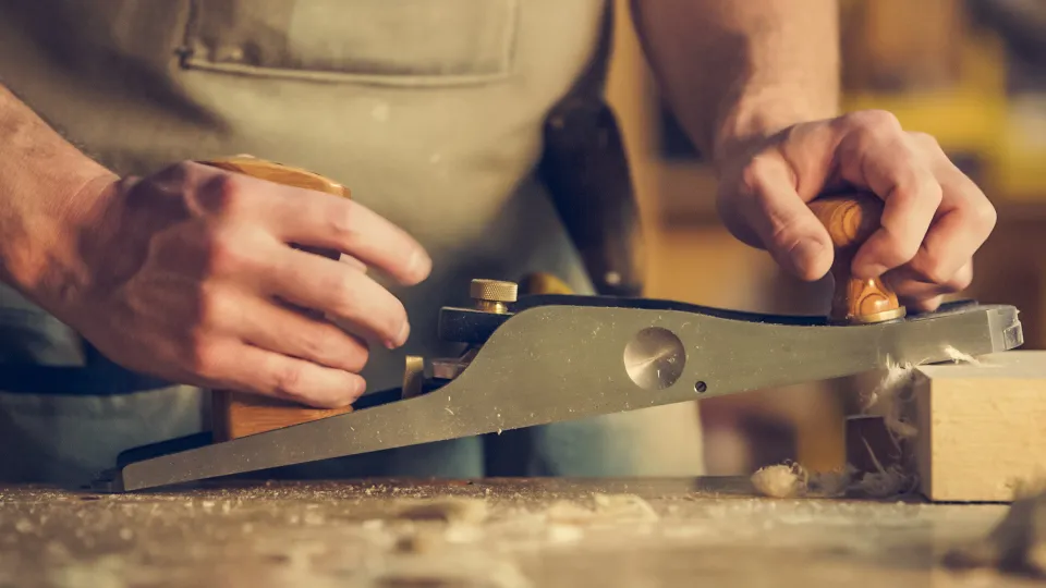 Artisan rabotant une pièce de bois dans son atelier